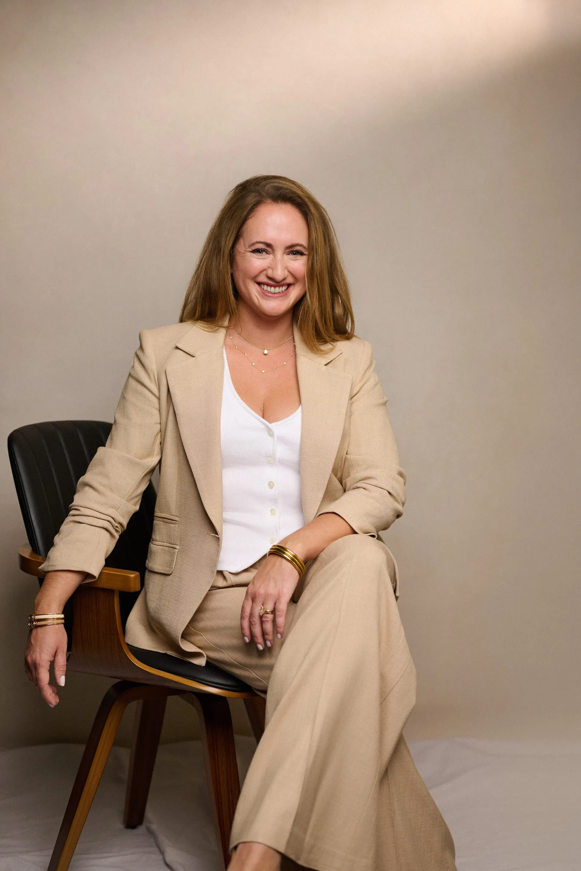 Anina Giannini seated in a cream suit for a personal brand portrait