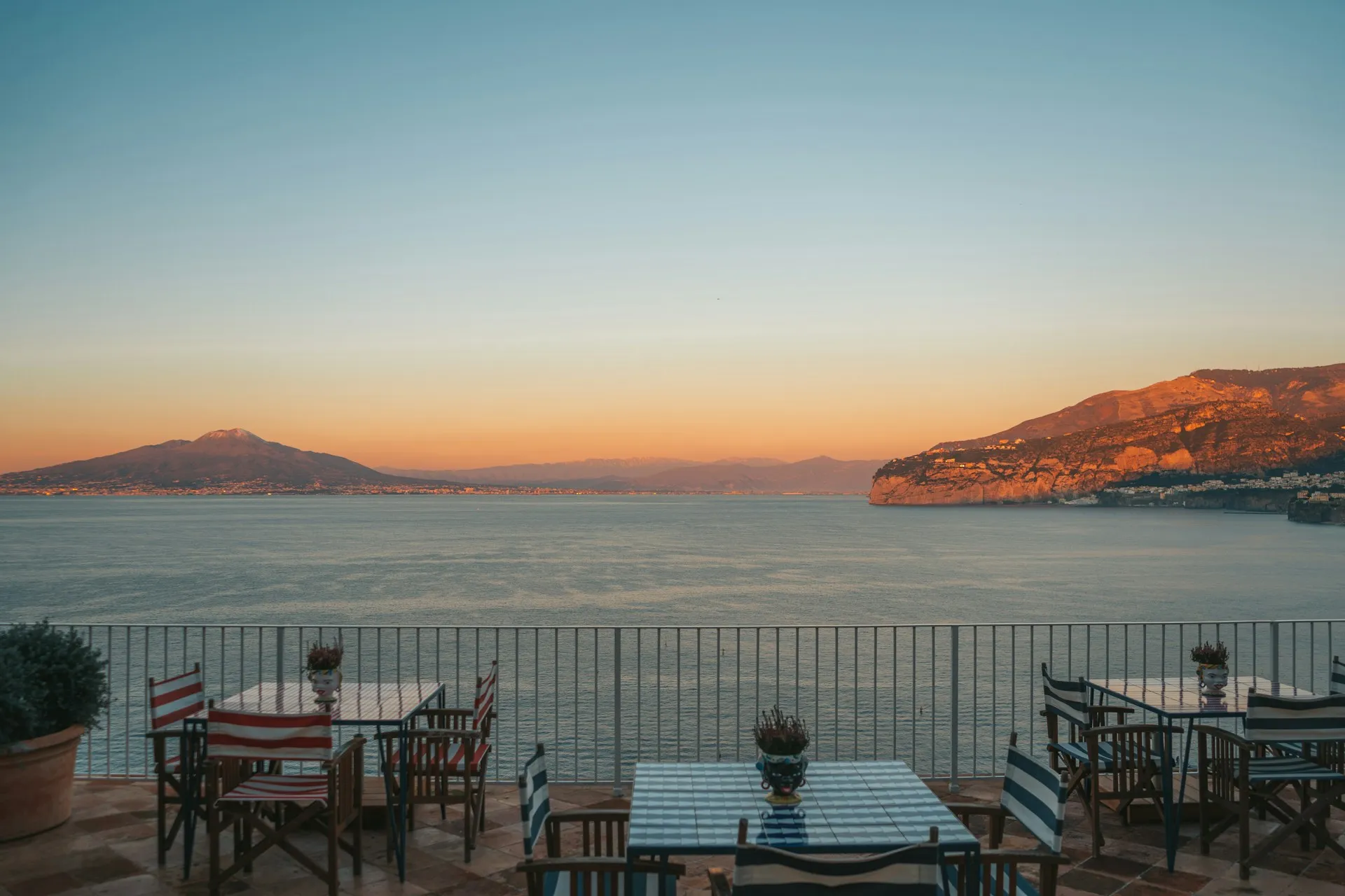 Café tables on a Mediterranean terrace above the sea at dusk